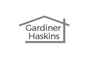 Logo with the text "Gardiner Haskins" inside a stylized house outline, featuring a pitched roof and horizontal base, all in gray on a white background. Perfect for showcasing their expertise in luxury bathrooms and exquisite bathroom design.