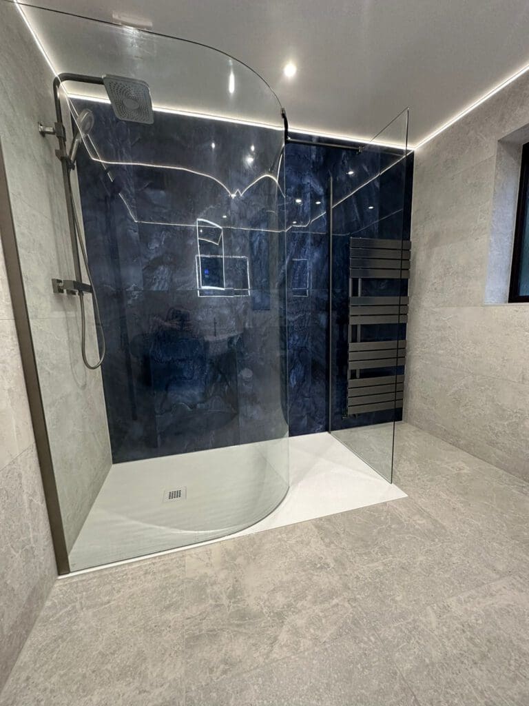 Modern bathroom featuring a luxury walk-in shower with a glass enclosure, dark tile accent wall, ceiling-mounted showerhead, and sleek metal towel rack. The room boasts light gray floor tiles and subtle recessed lighting, embodying exquisite bathroom design.